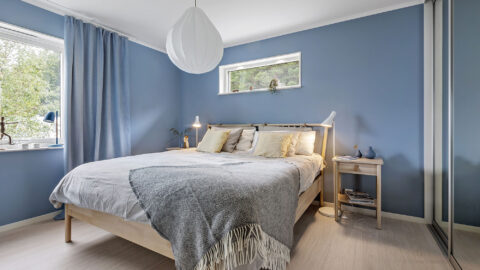 Blaues Schlafzimmer in weißem "Prio 141"-Holzhaus von Eksjöhus mit blauen Akzenten