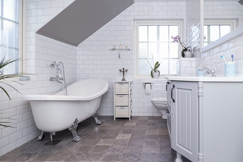 Weiß gefliestes Bad im Landhausstil mit nostalgischer Badewanne auf Metallfüßen
