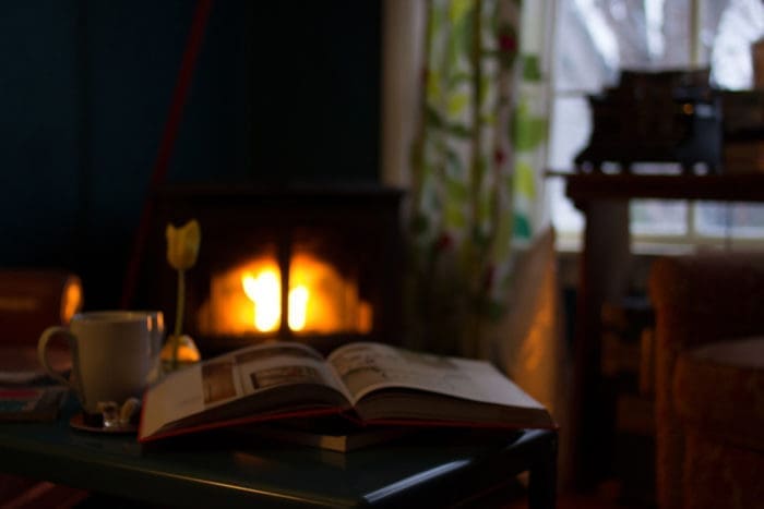 Aufgeklapptes Buch in dunklem Zimmer vor unscharfem Kaminofen