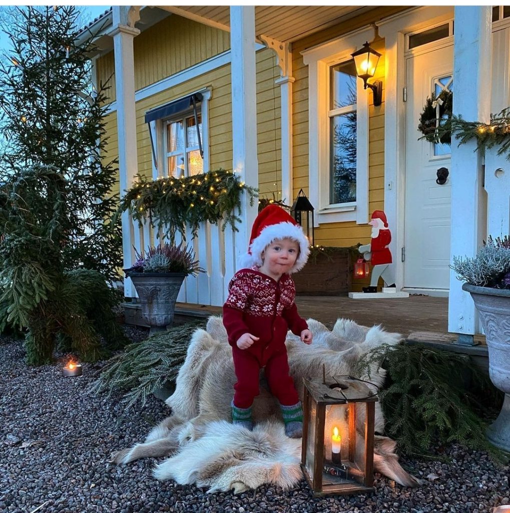 Schwedenhäuser in Weihnachtsstimmung: geschmückte Veranda und Kind mit Nikolausmütze