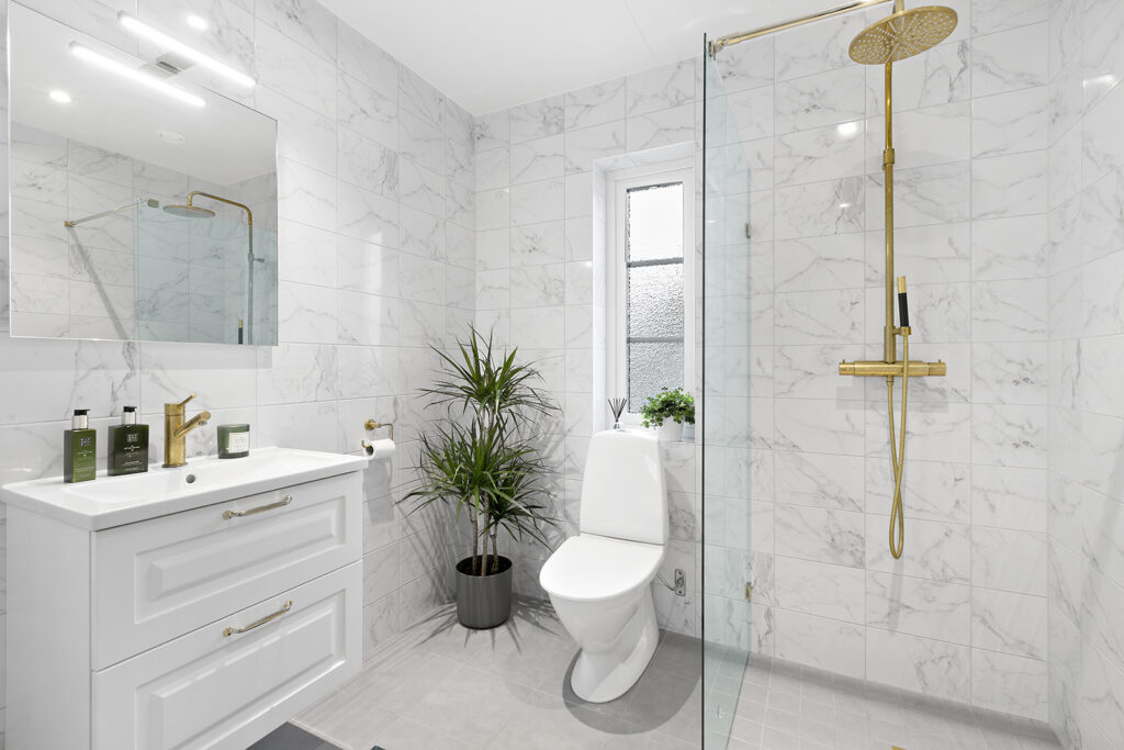 Badezimmer mit Fliesen im Marmor-Look und mit kupferfarbener Regendusche in Haus von Eksjöhus