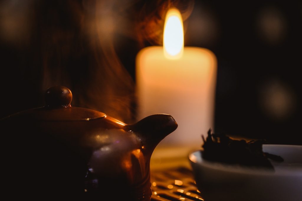 Tönerne Teekanne vor brennender Kerze