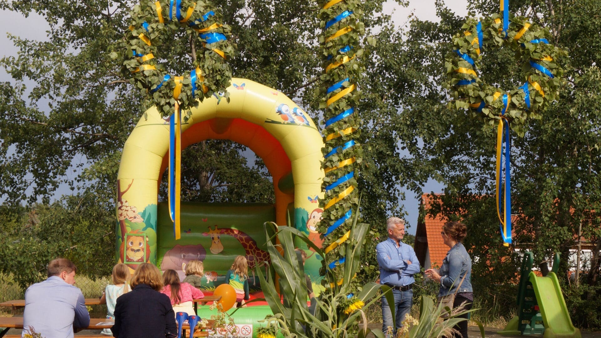 Hüpfburg hinter Maibaum bei Mittsommerfest